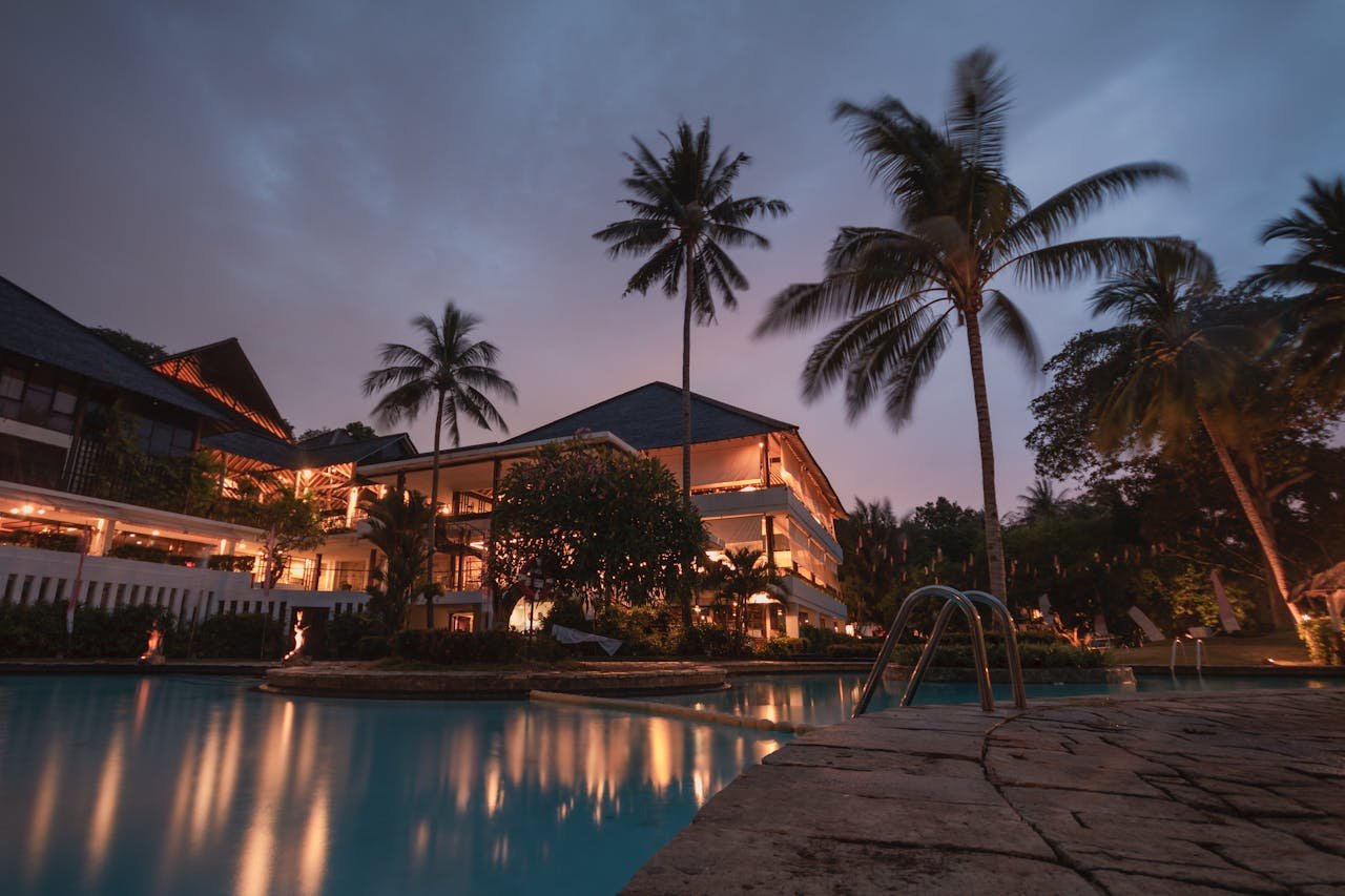services-03 Luxurious tropical resort with swimming pool and palms at dusk, perfect for a tranquil vacation.